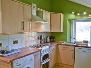 a kitchen with wooden cabinets and a stove top oven at Oak Cottage-16498 in Catcleugh