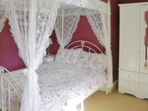 1 dormitorio con cama blanca con dosel y cortinas blancas en Oak Cottage-16498, en Catcleugh