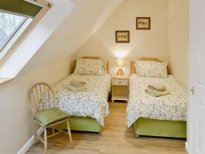 two twin beds in a attic bedroom with a chair at Bird Barn in Swanton Abbot