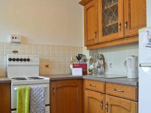 a kitchen with wooden cabinets and a white stove top oven at Gwenallt in Trevor