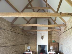 a room with a brick wall and wooden beams at The Cotswold Barn in Ampney Crucis