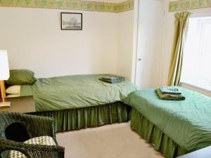 a bedroom with two beds and a chair and a window at Meadow Cottage-e1793 in Broadwindsor