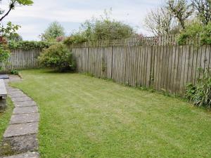 a fence in a backyard with a grass yard at Meadow Cottage-e1793 in Broadwindsor