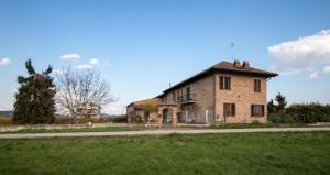 an old brick building in a field next to a road at Dolce Vita in CastellʼAlfero