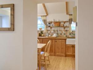 a kitchen with wooden cabinets and a table at Meadow Cottage in St. Just