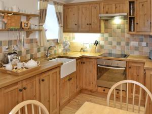 una cocina con armarios de madera y fregadero en Meadow Cottage en St Just