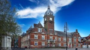 a large red brick building with a clock tower at Davies House - Modern King Beds, free parking, wifi, Contractors. in Swindon