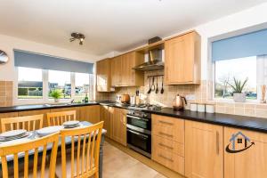 a kitchen with wooden cabinets and black counter tops at Davies House - Modern King Beds, free parking, wifi, Contractors. in Swindon