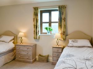 2 camas individuales en un dormitorio con ventana en Blackthorn Cottage, en Norton Disney