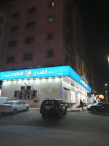 un'auto parcheggiata di fronte a un negozio di notte di احلام الشاطئ للشقق المفروشة a Ar Ruʼays