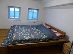 a bedroom with a bed with a comforter and two windows at Ferienwohnung Schindewolf in Grebenstein