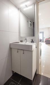 Baño blanco con lavabo y espejo en Kalafatis Downtown Apartment, en Itea