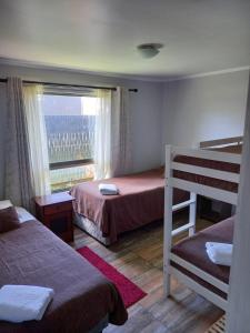 プエルト・アイセンにあるAysen Bike Cabañasのベッドルーム1室(二段ベッド2台、窓付)が備わります。