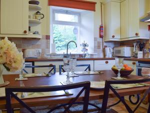 a kitchen with a wooden table with chairs and a sink at Glebe Cottage in New Scone