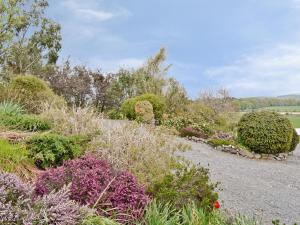 un jardín con arbustos y flores en un camino de grava en The Hen Hoose en Creebridge