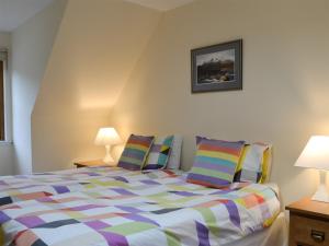 a bedroom with a bed with colorful pillows at Taigh Seonaig in Glencoe