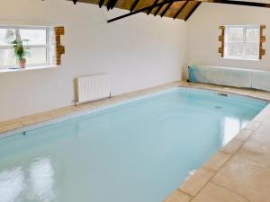uma piscina com água azul num quarto com duas janelas em The Old Piggeries em Loders