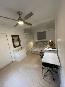 a bedroom with a bed and a desk and a ceiling fan at Comfortable modern apartment- central location. in Miami