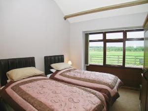 two beds in a room with a window at Rising Sun Holiday Cottage in Aldwark