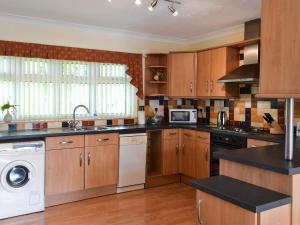 a kitchen with wooden cabinets and a washer and dryer at Bridge End Farm in Frosterley