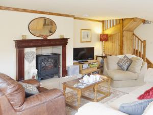 a living room with a fireplace and a couch and chairs at Yr Wyddfa in Caeathro