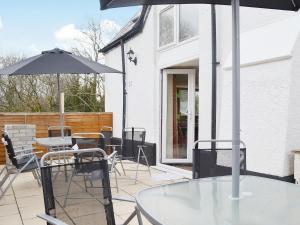 a patio with a table and chairs and an umbrella at Yr Wyddfa in Caeathro