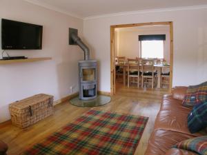 a living room with a couch and a fireplace at Rowan Cottage in Carrbridge