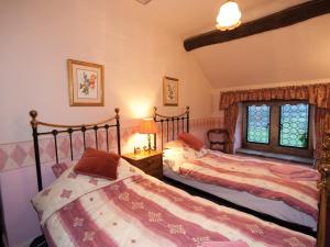 キャッスルトンにあるMullions Cottageのベッドルーム1室(ベッド2台、窓付)