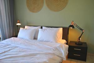 a bedroom with a bed with white sheets and a lamp at Houseloft Meteora Spirit in Tríkala