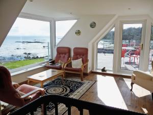a living room with two chairs and a view of the ocean at South Bay Cottage in Saasaig