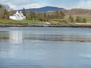 a white house on the shore of a body of water at South Bay Cottage in Saasaig