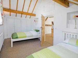 ノース・ウォルシャムにあるCountry Barnの白い壁と木製の天井が特徴の客室で、ベッド2台が備わります。