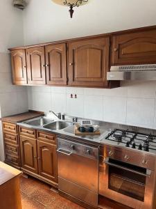 - une cuisine avec des placards en bois et une cuisinière en acier inoxydable dans l'établissement Accogliente appartamento a 25 minuti da milano, à Parabiago