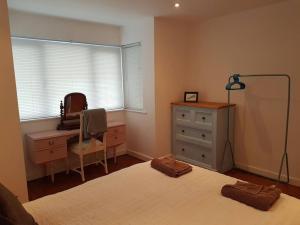 a bedroom with a bed and a dresser and a desk at Atlantic Retreat - 5 minute stroll from the beach in Bude