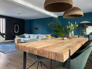 een eetkamer met een houten tafel en een bank bij Spacious appartement in scenic quarter with huge roof terrace in Breda