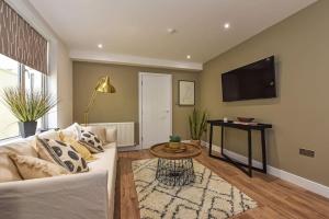 a living room with a white couch and a tv at Modern Two Bed with En-Suites and Private Parking in Cardiff