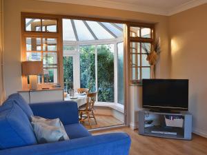 a living room with a blue couch and a tv at Harbour Cottage in Winterton-on-Sea