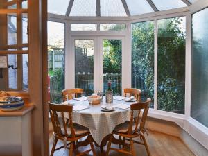 uma sala de jantar com uma mesa com cadeiras e janelas em Harbour Cottage em Winterton-on-Sea