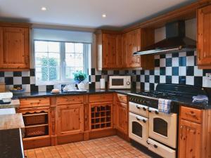 uma cozinha com armários de madeira e um forno com placa de fogão em Harbour Cottage em Winterton-on-Sea