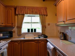 a kitchen with a sink and a window at Busy Lizzie Cottage-mfo in Akeld