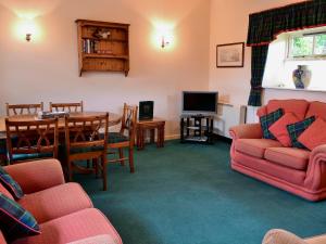 a living room with a table and chairs and a tv at Busy Lizzie Cottage-mfo in Akeld