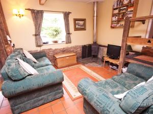 a living room with two couches and a television at Rye Court Cottage in Birtsmorton