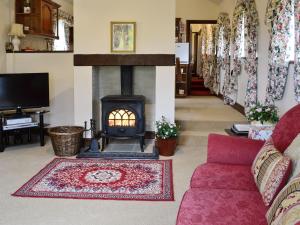 a living room with a fireplace and a red couch at Primrose Cottage - Lpg in Ireby