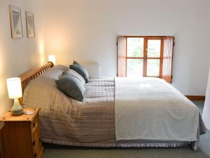 een slaapkamer met een bed met kussens en een raam bij Bruces Cottage in Saint Erth