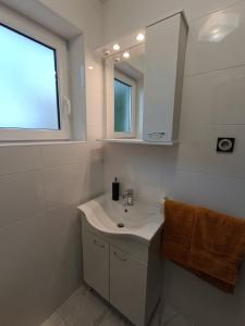 ein weißes Badezimmer mit einem Waschbecken und einem Spiegel in der Unterkunft Apartments Mira Krk in Krk