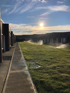 een grasveld met gebouwen en de zon in de lucht bij primitivo complejo in Comandante Luis Piedra Buena