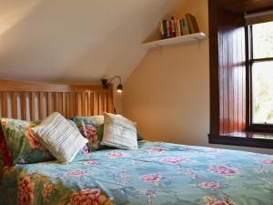 a bed with a blue comforter and pillows at Garden Cottage in Weem