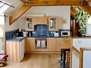 a kitchen with wooden cabinets and a table at Bats Roost - Hkkp in Lynton