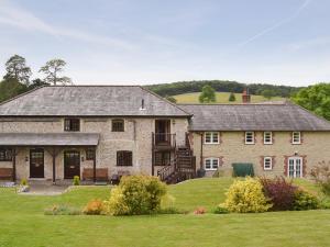 a large stone house with a grass yard at Stable Cottage in East Meon