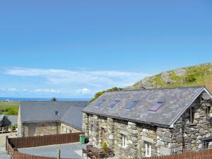 a stone building with solar panels on its roof at Hen Ysgubor - 29518 in Fairbourne